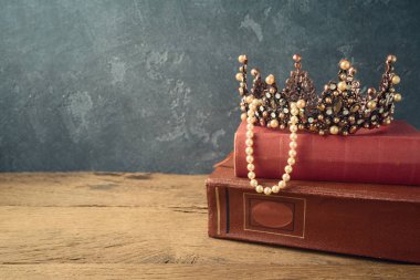 Karanlık giriş üzerinde ahşap masada peri masalı taç ve eski kitaplar