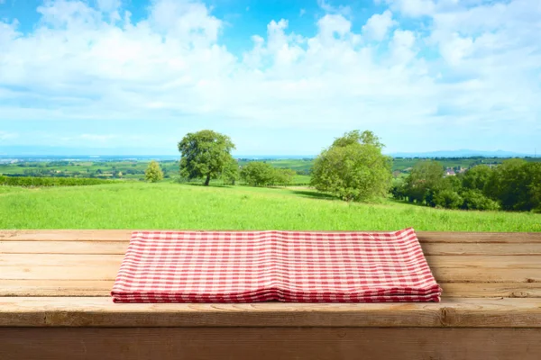 Пустой деревянный стол со скатертью на фоне летних лугов — стоковое фото