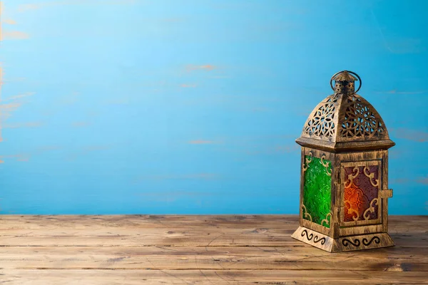 Lanterna iluminada na mesa de madeira sobre fundo azul . — Fotografia de Stock