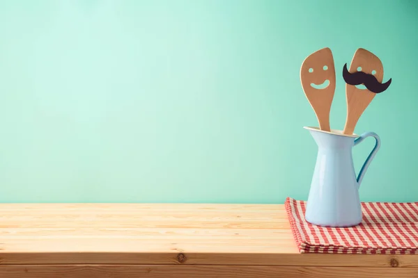 Küchenutensilien in blauer Kanne auf Holztisch — Stockfoto
