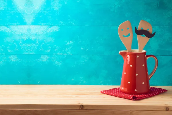 Kitchen cute utensils in red jug on wooden table. — Stock Photo, Image