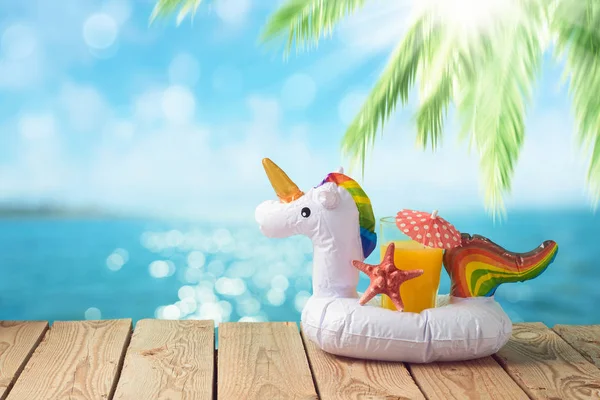 Summer vacation concept with orange juice and unicorn pool float — Stock Photo, Image