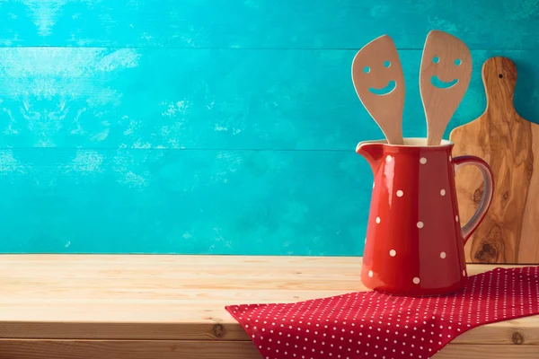 Kitchen cute utensils in red jug on wooden table — Stock Photo, Image