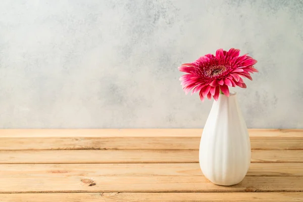 Flor de gerbera rosa em vaso na mesa de madeira — Fotografia de Stock