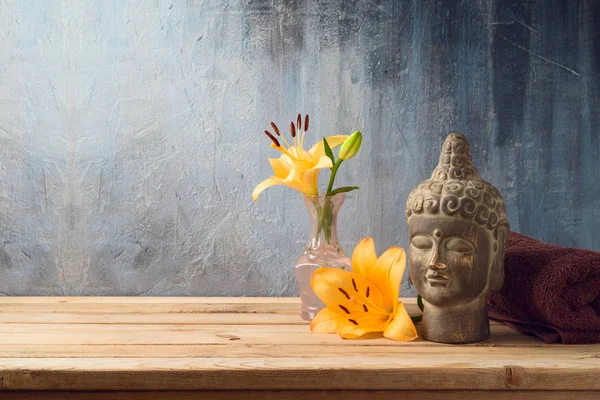 Buddha-Statue, Blumen und Handtuch auf Holztisch über dunklem Rücken — Stockfoto
