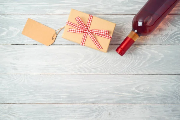 木桌背景上的礼品盒、一瓶葡萄酒和礼品标签 — 图库照片