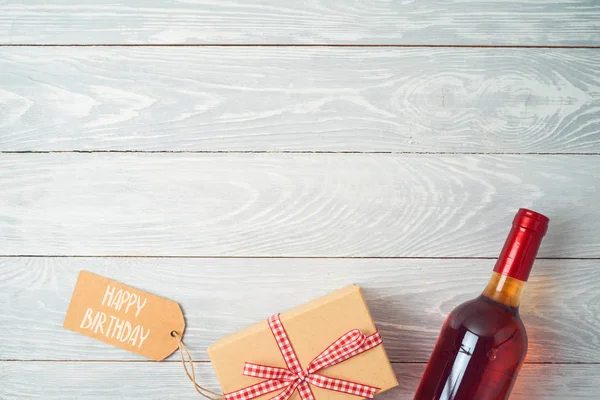 木桌背景上的礼品盒、一瓶葡萄酒和礼品标签 — 图库照片