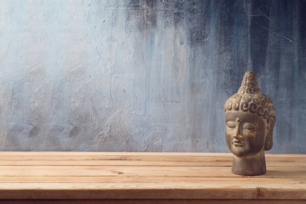Buddha statue on wooden table over dark background