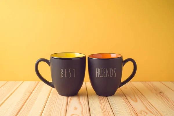 Chalkboard coffee mugs on wooden table with best friends text. F