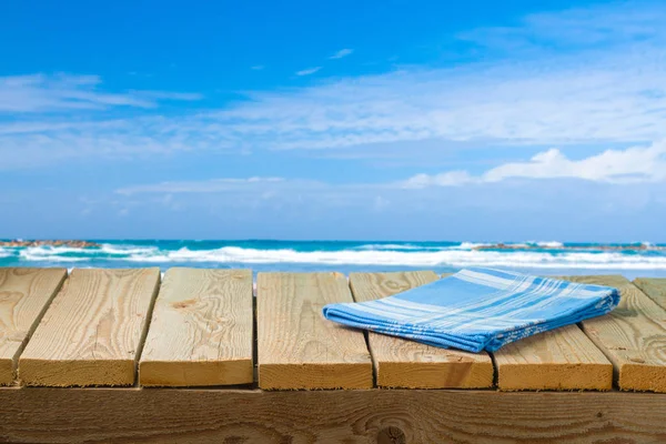 Empty wooden table with tablecloth over sea beach background — Stock Photo, Image