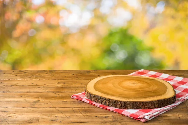 Lege houten tafel met tafelkleed en houten plank over de herfst — Stockfoto