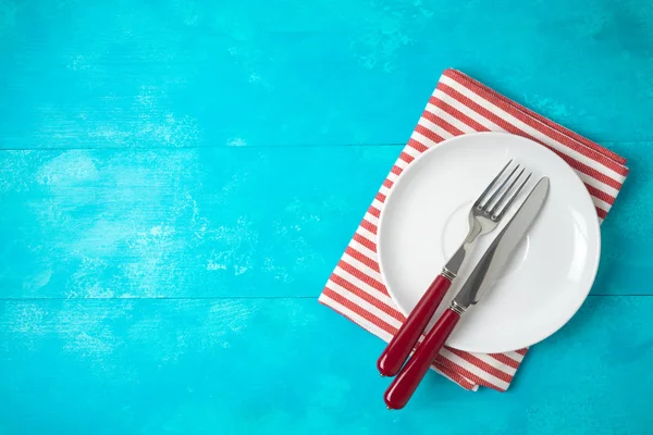 Assiette vide blanche et nappe rayée rouge sur fond en bois bleu — Photo