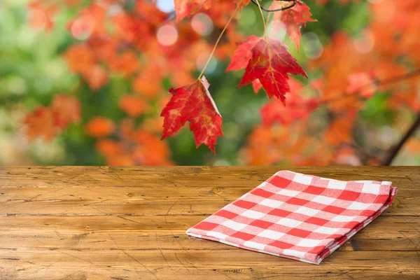 Άδειο ξύλινο τραπέζι με τραπεζομάντιλο πάνω από το φθινόπωρο φύση πάρκο πίσω — Φωτογραφία Αρχείου