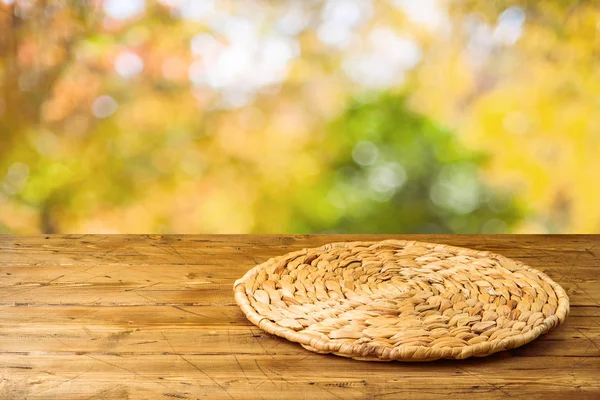 Table en bois vide avec napperon rond en osier sur la nature d'automne — Photo