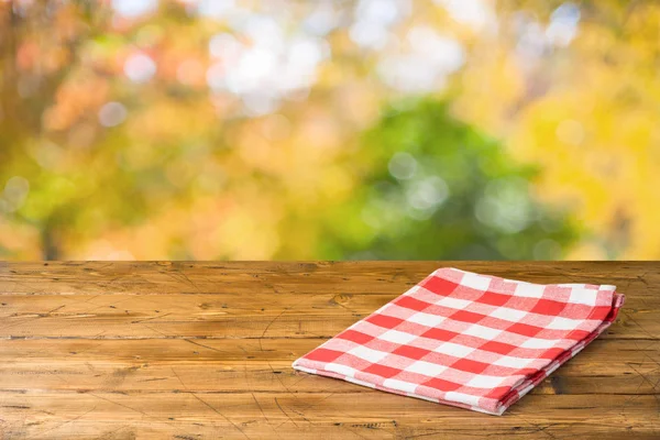 Empty wooden table with tablecloth over autumn nature park backg — Stock Photo, Image