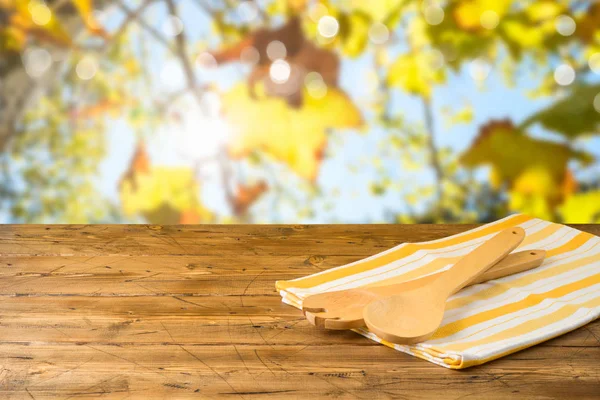 秋のボケの上に木製のテーブルの上の台所用品とテーブルクロス — ストック写真