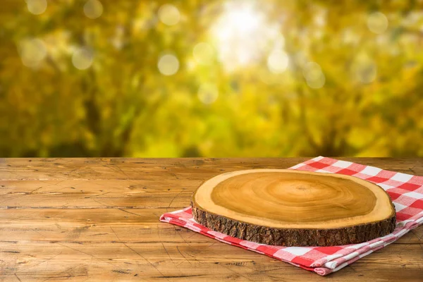Empty wooden table with tablecloth and wooden board over autumn — Stock Photo, Image