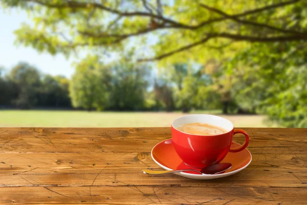 Copo de café vermelho na mesa de madeira sobre o fundo do bokeh outono — Fotografia de Stock