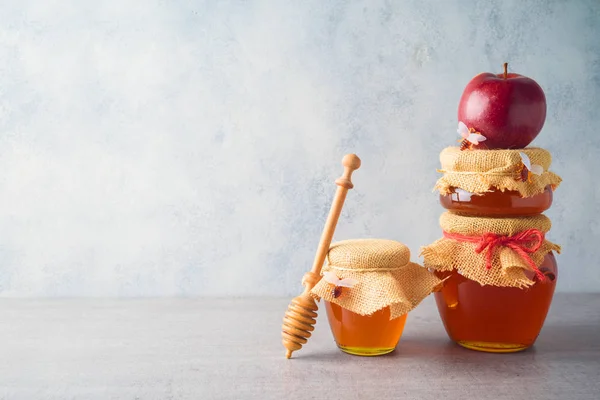 Vasi di miele e mela su sfondo grigio — Foto Stock