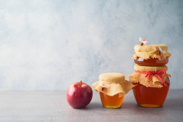 Frascos de miel y manzana sobre fondo gris —  Fotos de Stock