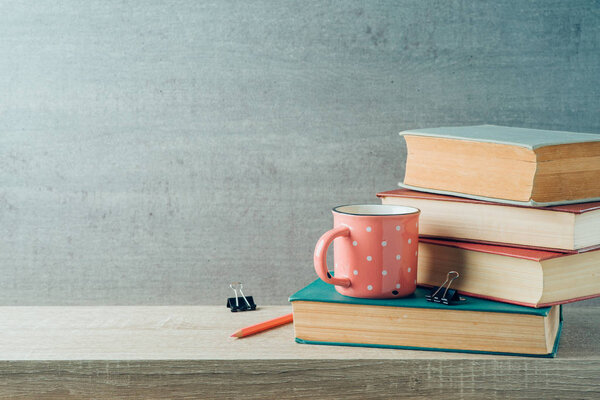 Back to school concept with coffee cup and books on wooden shelf