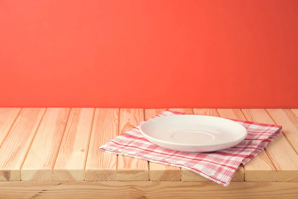 Weihnachtlicher Holztisch mit leerem Teller und Tischdecke über Rot — Stockfoto