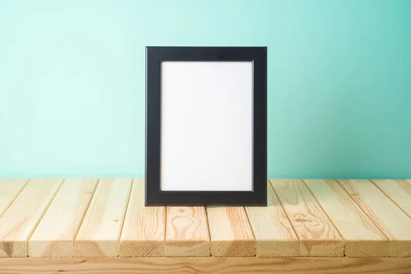 Photo frame mockup on wooden table over blue background — Stock Photo, Image