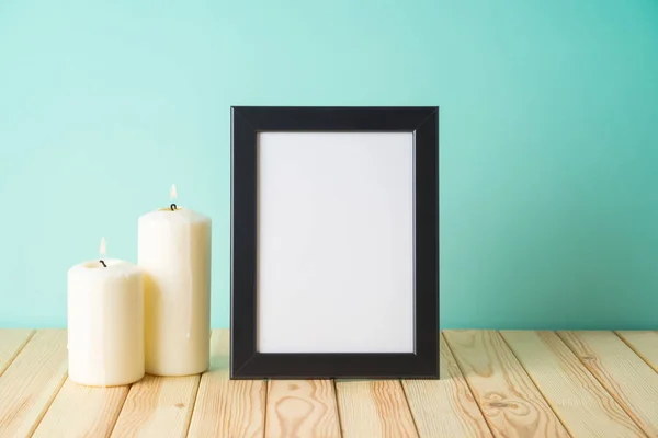 Foto moldura mockup e velas na mesa de madeira sobre backgro azul — Fotografia de Stock