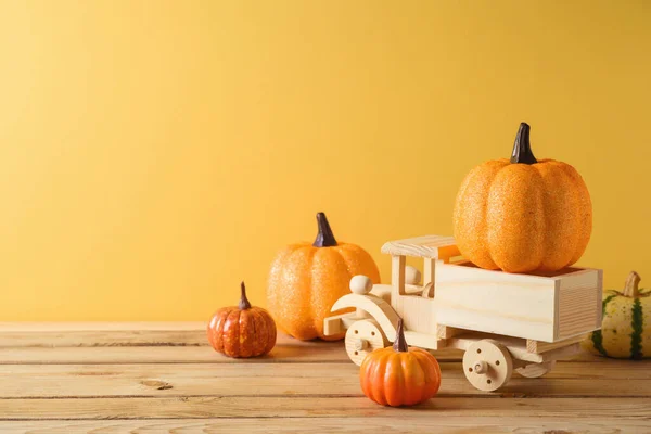 黄色の背景に木製のテーブルの上におもちゃのトラックやカボチャの装飾と感謝祭の装飾コンセプト 秋のグリーティングカード — ストック写真