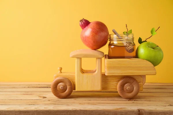 犹太假日Rosh Hashana的概念 玩具卡车 石榴和苹果放在木制桌子上 黄色背景 — 图库照片