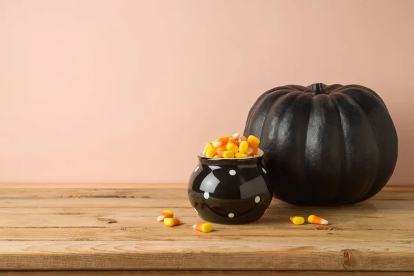 キャンディーコーンと木製のテーブルの上に黒いカボチャの装飾とハロウィーンの休日のお祝いのコンセプト — ストック写真