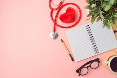 Not defteri, Doktor Steteskop, pembe arka planda bitki ve kahve fincanı gibi. Tıbbi sağlık hizmeti konsepti. Üst manzara, düz uzanma