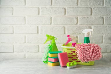 Çevre dostu yeşil temizlik şişeleri ve malzeme beyaz ahşap masa üzerinde tuğla duvar arka planı. Bahar temizliği kavramı