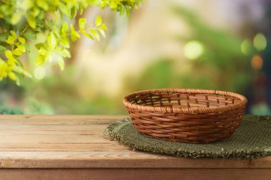 Boş sepet ve masa örtüsü yeşil bahçe arka planında tahta masa örtüsü. Yay tasarım ve ürün gösterimi için tasarlandı.