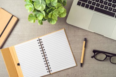 Defter dizüstü bilgisayarla modellenir ve modern ofis masasına yerleştirilir. Üst manzara, düz uzanma