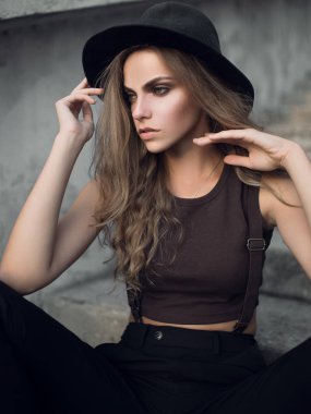 Siyah şık şapka ve kısa kahverengi üst sevimli genç beyaz beyaz kız portresi. Gün batımında seksi bir kızın moda portre.