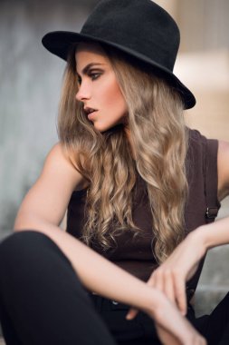Siyah şık şapka ve kısa kahverengi üst sevimli genç beyaz beyaz kız portresi. Gün batımında seksi bir kızın moda portre.