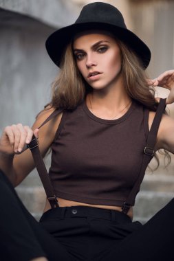 Siyah şık şapka ve kısa kahverengi üst sevimli genç beyaz beyaz kız portresi. Gün batımında seksi bir kızın moda portre.