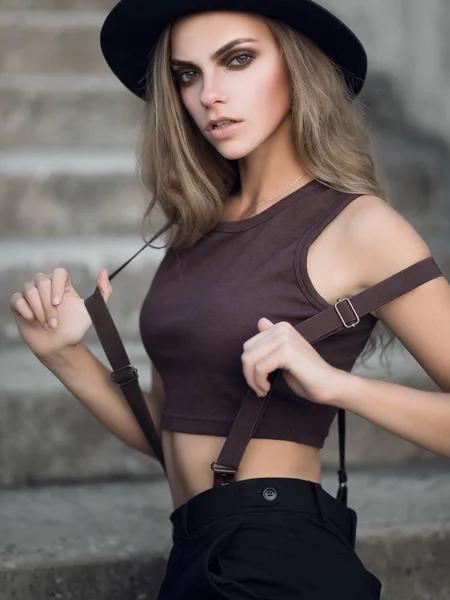 一个可爱的年轻白种白人女孩的肖像在黑色时尚的帽子和短棕色顶部 日落时性感女孩的时尚肖像 — 图库照片