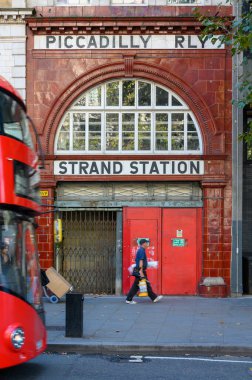23 Eylül 2019 'da Strand' daki kullanılmayan Aldwych metro istasyonuna giriş ve Londra 'da bir çift katlı otobüs geçmek üzere.