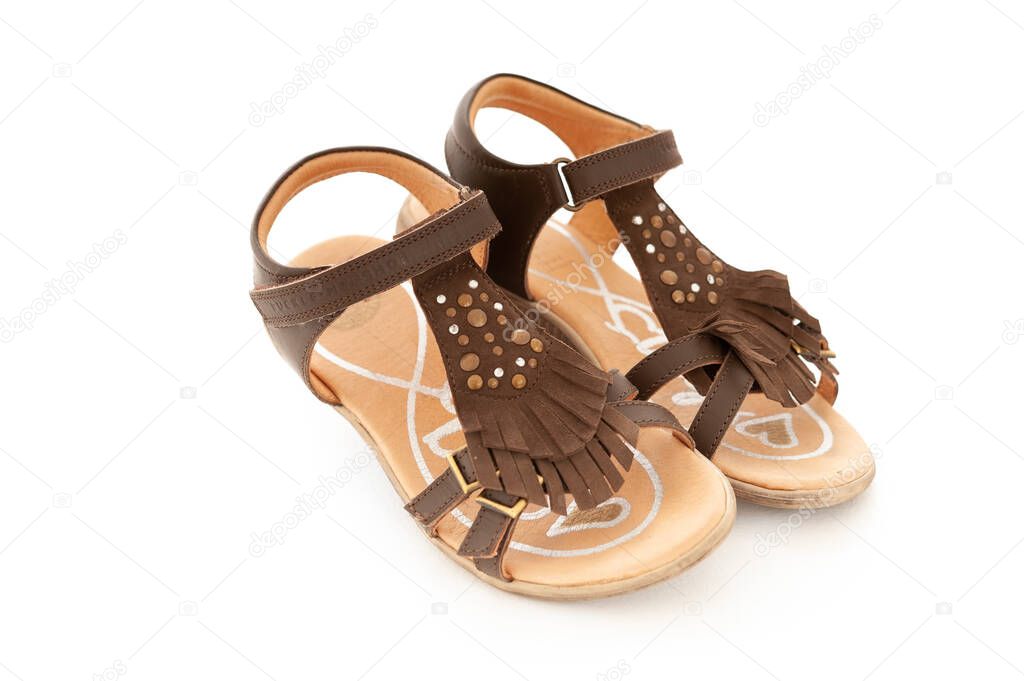 A pair of girls brown decorated sandals with tassles isolated on white studio background.