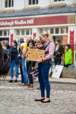 Richmond, Kuzey Yorkshire, İngiltere - 14 Haziran 2020: Bir anne, Richmond North Yorkshire 'daki bir Siyahi Yaşamı Önemi Protestosu' nda küçük bir çocuk ve ev yapımı bir tabela tutuyor