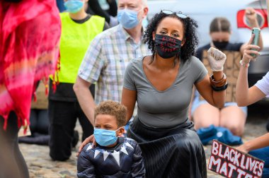 Richmond, Kuzey Yorkshire, İngiltere - 14 Haziran 2020: Bir kadın Kuzey Yorkshire, Richmond 'da düzenlenen BLM protestosunda Siyah Yaşamlar Önemli PPE Yüz Maskesi takıyor ve oğlunu selamlıyor
