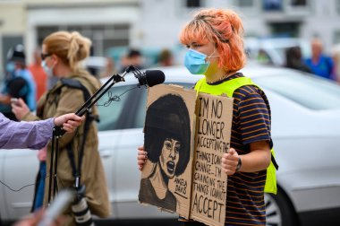 Richmond, Kuzey Yorkshire, İngiltere - 14 Haziran 2020: Siyahların Yaşamı Önemlidir mitinginde beyaz bir kadın protestocu, röportaj sırasında ev yapımı bir ırkçılık karşıtı tabela tutuyor