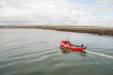 Sakin bir günde küçük kırmızı bir balıkçı teknesi.