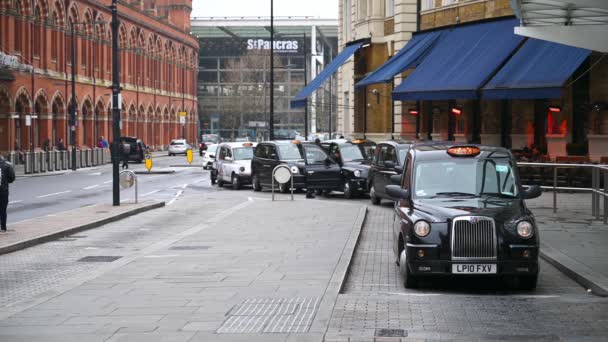 ロンドン 2020年3月19日 ある男がキングス クロス セント パンクラス駅の外で待っている黒いロンドンのタクシーに乗り込む 救急車が青いライトが点滅して過去に突入すると女性は2番目のタクシーに入る — ストック動画