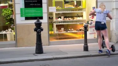 Vienna - 11 Temmuz 2019: Sarışın bir kadın kaldırıma elektrikli scooter park eder ve onu etkisiz hale getirmek için akıllı telefon kullanır.