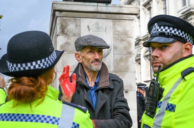 LONDON - 18 Ekim 2019: Soykırım İsyanı protestocusunun kırmızı boyalı elleriyle polis memurları tarafından çevrelenmesi
