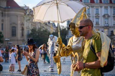 PRAG - 20 Temmuz 2019: Altın kadın heykel sokak sanatçısı Çek Cumhuriyeti 'nin Prag kentindeki The Old Town Square' de erkek bir turiste poz verdi