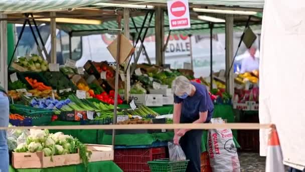 2020年8月1日イギリス ノースヨークシャー州リッチモンド 屋外の果物や野菜の市場の屋台で買い物中に保護顔マスクを身に着けている成熟した女性 — ストック動画